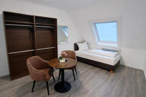 a small room with a bed and a table and chairs at Hotel Hansahof Bremen in Bremen