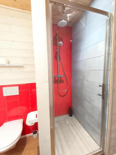 a shower in a bathroom with a red wall at Eco-lodges Lacanau Moutchic Inn - 4 pers in Lacanau