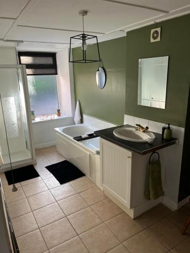 a bathroom with a tub and a sink and a bath tub at Hallow Cottage in Newtownstewart