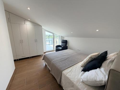 a white bedroom with a bed and a chair at Apartment Lasta Medulin in Medulin
