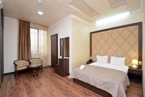 a hotel room with a large bed and a chair at Partez Hotel in Yerevan