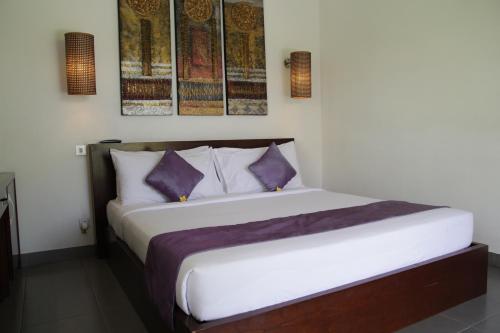 a bedroom with a bed with purple and white pillows at The Samara Villas & Restaurant in Ubud