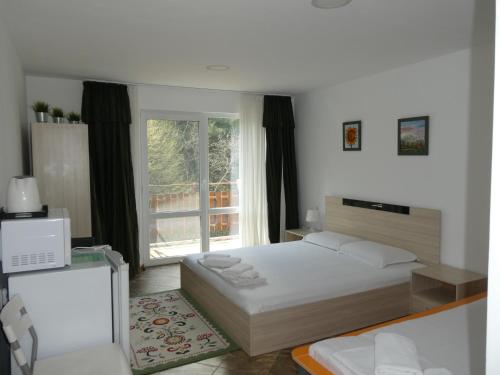a bedroom with a bed and a large window at Daskalov Bungalows in Chervena Lokva