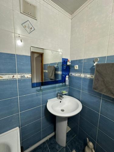 a blue and white bathroom with a sink and a mirror at Stay Osh in Osh