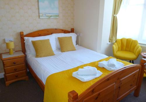 a bedroom with a bed with two towels on it at Brackenhurst Guest House in Skegness