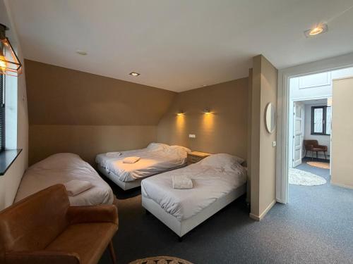 a hotel room with two beds and a chair at Thuysgrond in Bergeijk