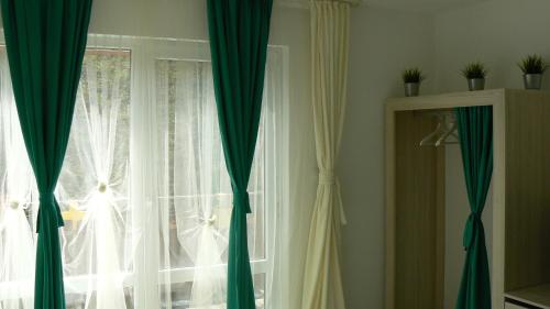 a window with green and white curtains in a room at Daskalov Bungalows in Chervena Lokva