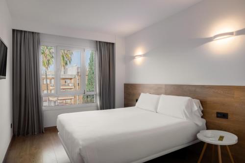 a bedroom with a large white bed and a window at Hotel SB Corona Tortosa in Tortosa