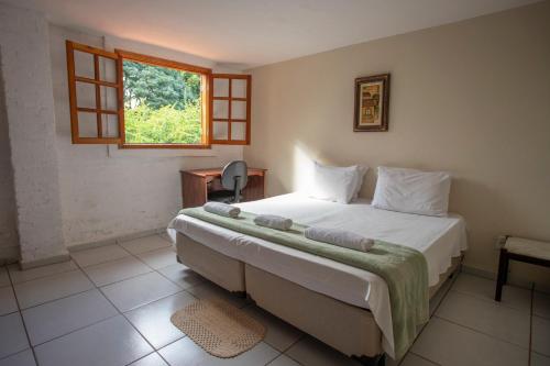 a bedroom with a large bed with a window at Pousada Campina do Monte Alegre in Campina do Monte Alegre