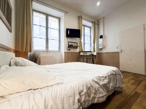 a bedroom with a large white bed and two windows at Studio Riom - Proche gare SNCF in Riom