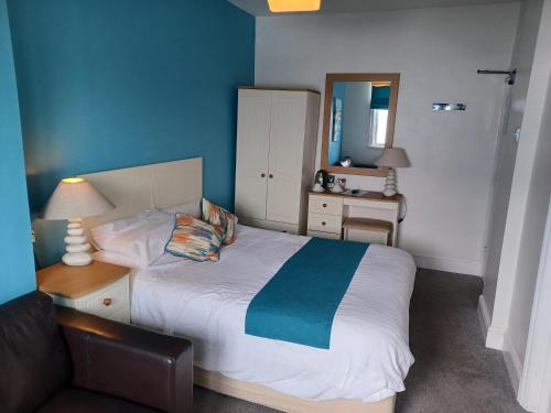 a bedroom with a bed and a chair and a mirror at The Paris Hotel in Coverack