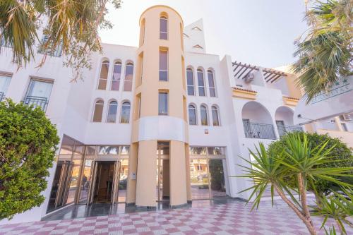 a large white building with palm trees in front of it at BLUESEA Brisa Roquetas in Roquetas de Mar