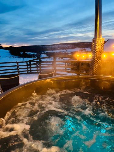 a jacuzzi tub on a balcony at night at The Niblet Bonnie View Glamping Cabins, Helmsley in Carlton