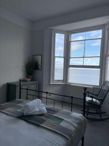 a bedroom with a bed and a chair and windows at Beds at 46, Cowes in Cowes