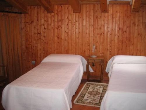 two beds in a room with wooden walls at Casa Rural Los Boteros in Pesquera de Duero