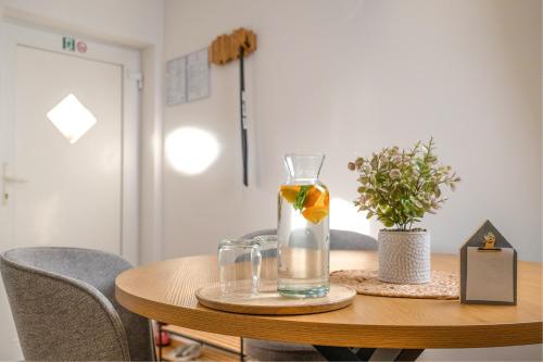 a table with a vase and two glasses on it at Red Maple Apartments in Maribor
