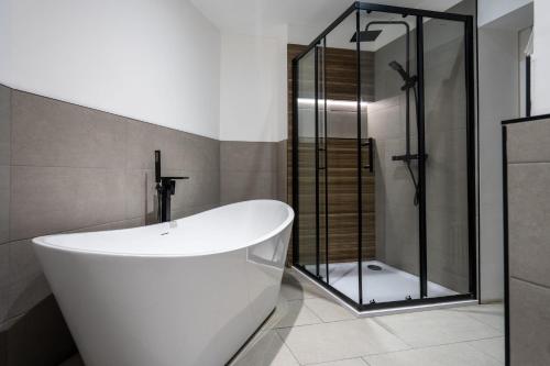 a white bath tub in a bathroom with a shower at Shoreditch Luxe in London