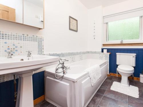 a bathroom with a tub and a toilet and a sink at 3 Bed in Inverness oc-in633 in Balnain