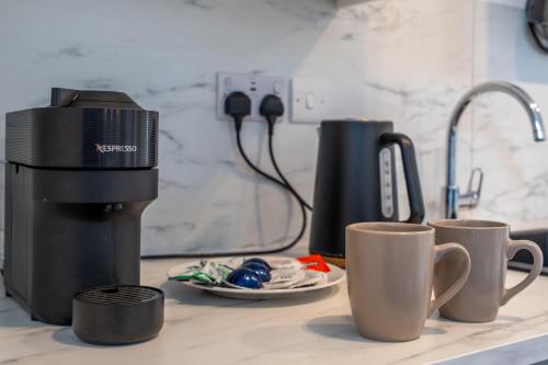 a counter with two coffee mugs and a coffee maker at Shoreditch Luxe in London