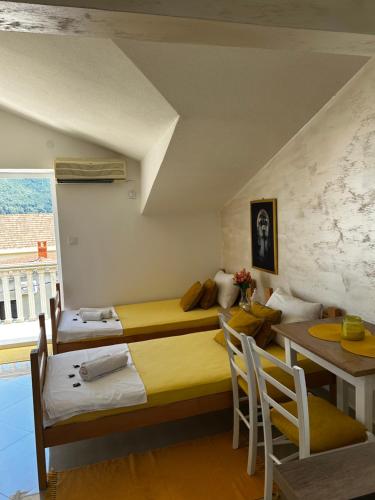a bedroom with two beds and a table and chairs at Apartmani Gušti in Kamenari