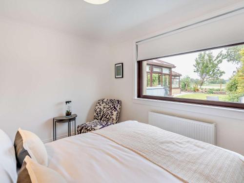 a bedroom with a bed and a window and a chair at 3 Bed in Falkirk oc-96124 in Avonbridge