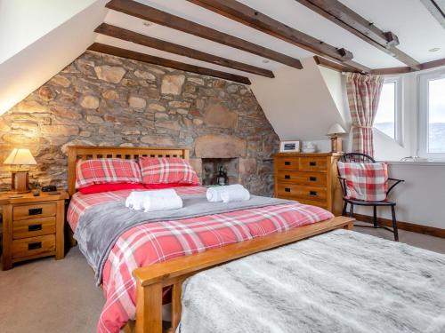 a bedroom with two beds and a stone wall at 2 Bed in Drumnadrochit oc-ca315 in Drumnadrochit