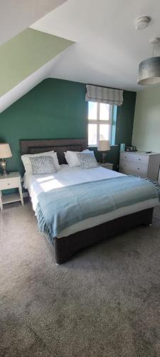 a bedroom with a large bed and a green wall at Dubhlinn House Accommodation in Doolin