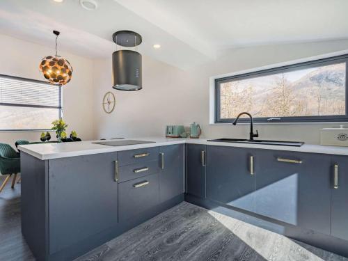 a kitchen with blue cabinets and a sink and a window at 3 Bed in Kinlochleven oc-87130 in Kinlochleven