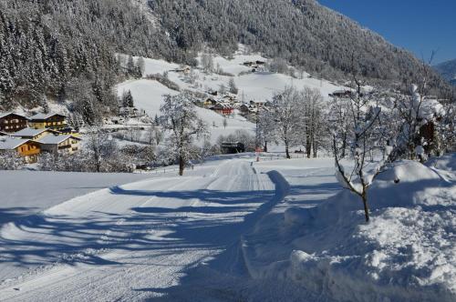 a snow covered road with a village in the distance at Ferienwohnung Bognerhof in Sankt Veit im Pongau