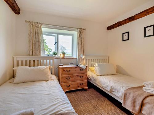 a bedroom with two beds and a dresser and a window at 3 Bed in Penrith oc-94982 in Pooley Bridge
