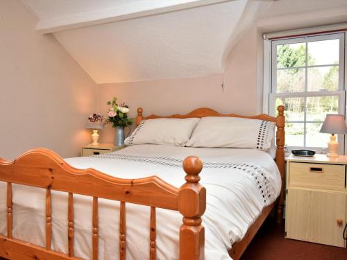 a bedroom with a wooden bed and a window at 3 Bed in Threlkeld oc-sz421 in Threlkeld