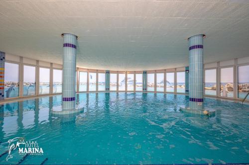 ein großes Schwimmbecken mit Säulen in einem Gebäude in der Unterkunft Hotel Marina in Selce
