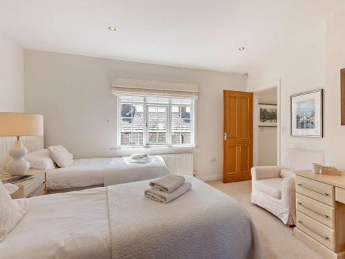 a white bedroom with two beds and a chair at 2 Bed in Cartmel oc-lcc47 in Cartmel