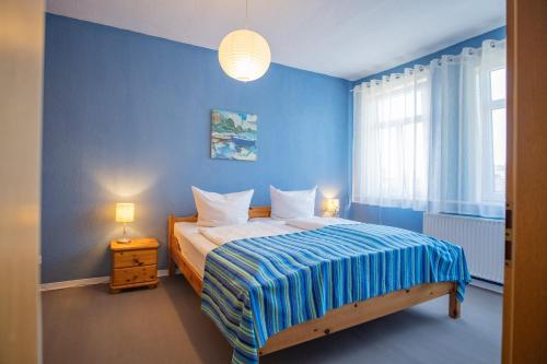 a blue bedroom with a bed and a window at Ferienhaus "Zum Lochstein" in Sankt Andreasberg
