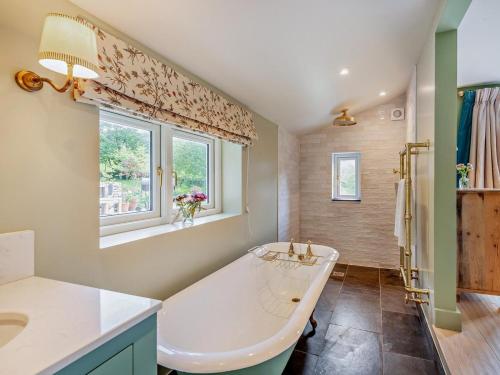 a bathroom with a tub and a sink and a window at 4 Bed in Kendal oc-sz535 in Kentmere
