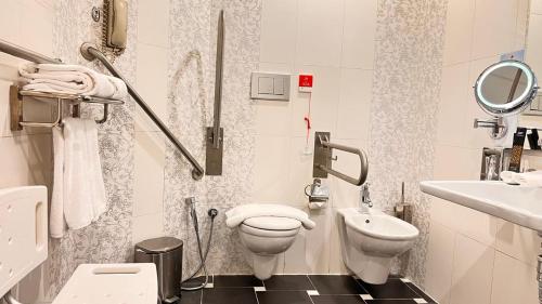 a white bathroom with a toilet and a sink at Awaliv Hotel in Taif