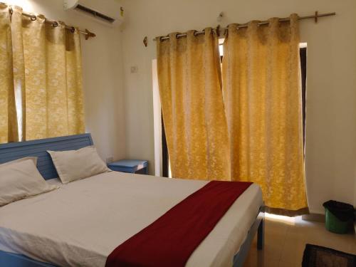 a bedroom with a bed and yellow curtains at The Coastal Villa Arpora in Parra