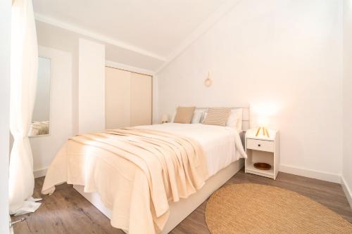 a white bedroom with a white bed and a rug at Attic Duplex Apartment with 4 terraces & 5 min walk to Beach in Denia