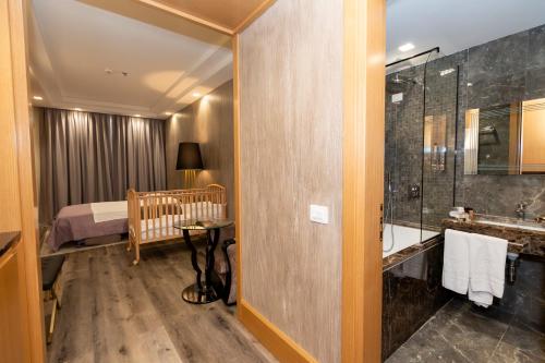 a bathroom with a bed and a shower and a crib at Hotel Golden Palace in Shkodër