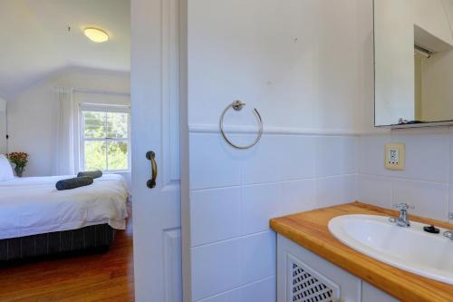 a bathroom with a sink and a bed with a window at Sunbird Cottage - Wilderness in Wilderness