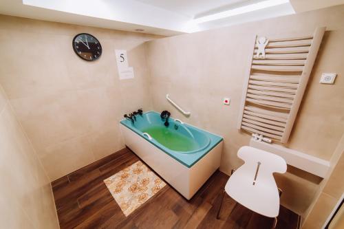 a bathroom with a tub and a toilet and a clock at Sanatorium Dedal in Polańczyk
