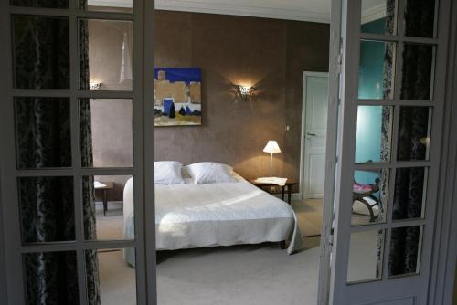 a bedroom with a white bed and a mirror at chambres de charme "Florence" in Ribérac
