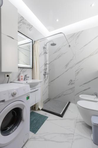 a white bathroom with a sink and a washing machine at Vila Emi Apartment's in Durrës