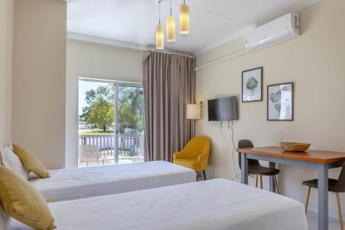a hotel room with two beds and a desk and a window at Kiss - Apartamentos in Albufeira