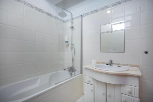 a white bathroom with a sink and a tub and a mirror at Kiss - Apartamentos in Albufeira