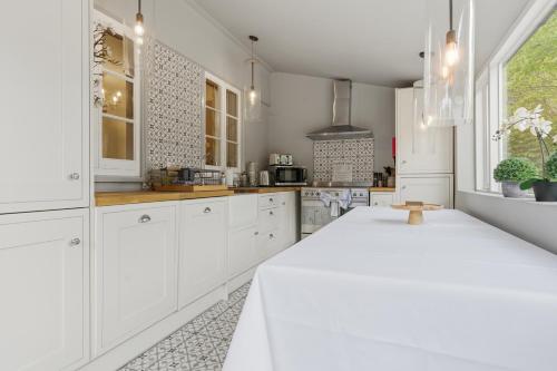 a white kitchen with white cabinets and a table at 2-Bedroom Cottage Sleeps 5 Free Parking in Harlow