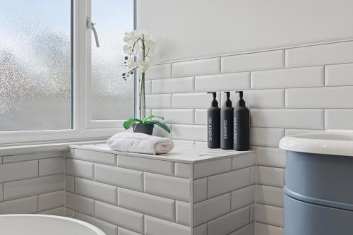 a bathroom with white subway tiles and a window at 2-Bedroom Cottage Sleeps 5 Free Parking in Harlow