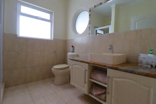 a bathroom with a sink and a toilet and a mirror at Sandy Greens Villa in Swakopmund