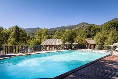 a swimming pool with a fence and mountains in the background at Huttopia Vallouise in Vallouise