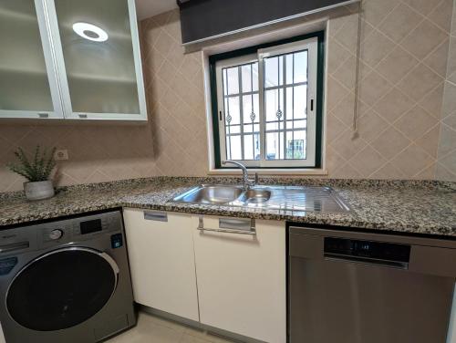 a kitchen with a sink and a washing machine at 5B Sra da Rocha - Casas & Papeis in Armação de Pêra